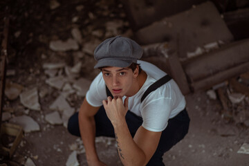 Joven en construcción abandonada vestido con gorro tiradores y camiseta