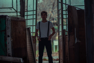 Joven en construcción abandonada vestido con gorro tiradores y camiseta