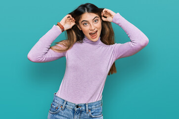 Young beautiful teen girl wearing turtleneck sweater smiling pulling ears with fingers, funny gesture. audition problem