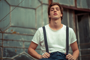 Joven en construcción abandonada vestido con gorro tiradores y camiseta