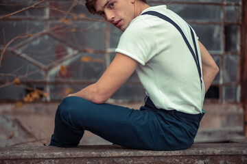 Joven en construcción abandonada vestido con gorro tiradores y camiseta