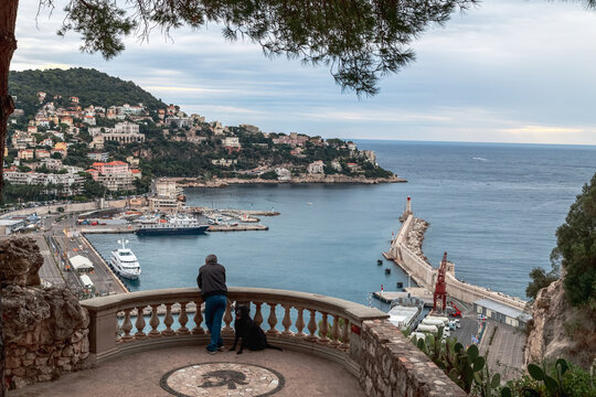 Nice, France. View of the old port of Nice, big cruise liners and lighthouse. Somebody enjoying the view. City on the hill in the background.