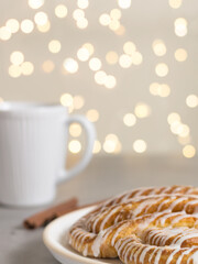 Cinnamon roll or cinnamon bun Dessert on plate with white cup of coffee. Classic American or French bakeries. Bokeh
