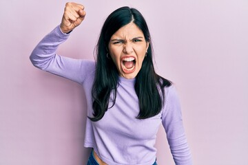 Young hispanic woman wearing casual clothes angry and mad raising fist frustrated and furious while shouting with anger. rage and aggressive concept.