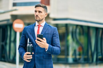 Young caucasian businessman with serious expression using smartphone at the city.