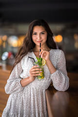 cute attractive brunette in a bar drinking mojito
