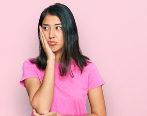 Beautiful asian young woman wearing casual pink t shirt thinking looking tired and bored with depression problems with crossed arms.