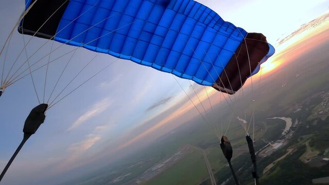 Personal perspective of skydiver piloting his parachute at the sunrise. 4K resolution.