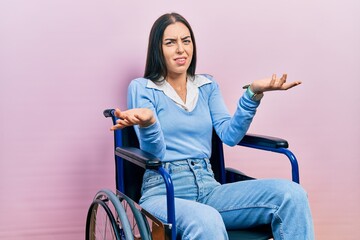 Beautiful woman with blue eyes sitting on wheelchair clueless and confused with open arms, no idea...