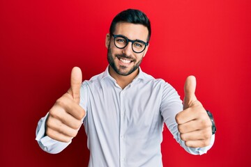 Young hispanic businessman wearing shirt and glasses approving doing positive gesture with hand,...