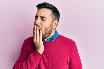 Young hispanic man wearing casual clothes bored yawning tired covering mouth with hand. restless and sleepiness.