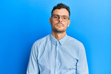 Young hispanic man wearing casual clothes and glasses looking sleepy and tired, exhausted for fatigue and hangover, lazy eyes in the morning.