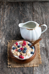 Rice and wholewheat cereal flakes with dried and fresh berries on wooden table