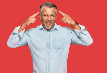 Fototapeta premium Middle age grey-haired man wearing casual clothes smiling pointing to head with both hands finger, great idea or thought, good memory