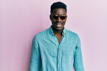 Obraz premium Handsome business black man wearing stylish sunglasses looking positive and happy standing and smiling with a confident smile showing teeth