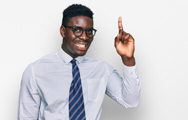 Handsome business black man wearing white shirt and tie pointing finger up with successful idea. exited and happy. number one.