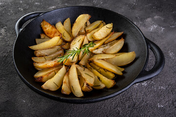 Potatoes baked in iron casserole with rosemary and olive oil