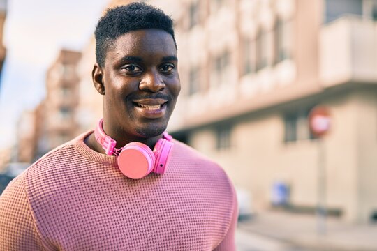 Young african american man smiling happy using headphones at the city.