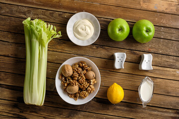 Ingredients for making a Waldorf salad made of celery, apples and walnuts on a rustic wooden background