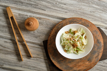 Waldorf salad with celery, apples and walnuts on a light wooden background