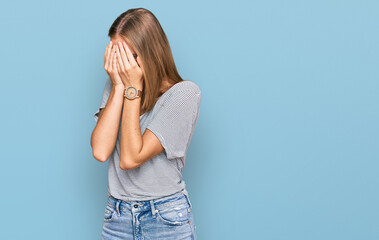 Beautiful young blonde woman wearing casual clothes and glasses with sad expression covering face with hands while crying. depression concept.