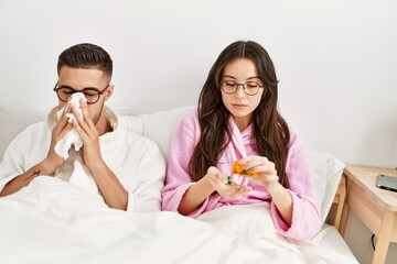 Young hispanic couple sick lying in bed at home.