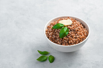 Natural, healthy boiled buckwheat with butter on a gray background.