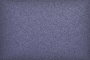 The surface of purple blue cardboard. Grey paper texture with cellulose fibers. Generic gray tinted background with vignetting. Dark summer paperboard wallpaper. Top-down. Macro
