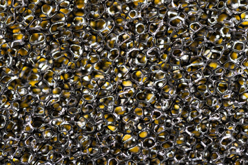 Black sponge macro abstraction texture on a yellow background