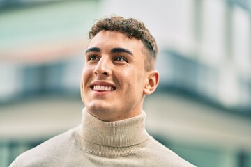 Young hispanic man smiling happy standing at the city.