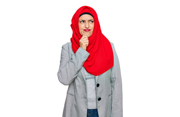 Beautiful hispanic woman wearing traditional islamic hijab scarf serious face thinking about question with hand on chin, thoughtful about confusing idea