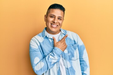 Young latin man wearing casual clothes smiling cheerful pointing with hand and finger up to the side