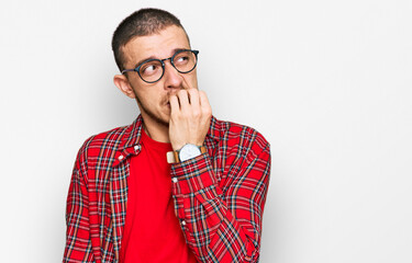 Hispanic young man wearing casual clothes looking stressed and nervous with hands on mouth biting...