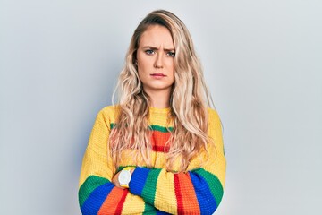 Beautiful young blonde woman wearing colored sweater skeptic and nervous, disapproving expression on face with crossed arms. negative person.