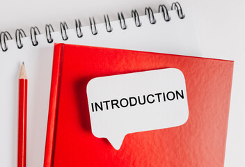 Text Introduction a white sticker on red notepad with office stationery background. Flat lay on business, finance and development concept