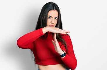 Young brunette teenager wearing red turtleneck sweater doing time out gesture with hands,...