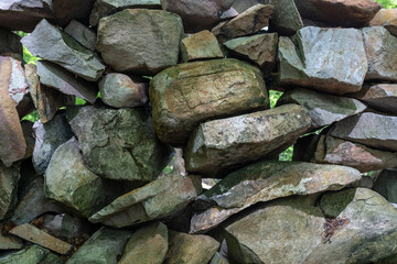 Closeup of a simple dry one-layer stone wall with many gaps made of quartzite stones.