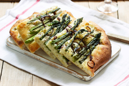 Focaccia or pizza with asparagus, onions, olives and herbs. Rustic style.