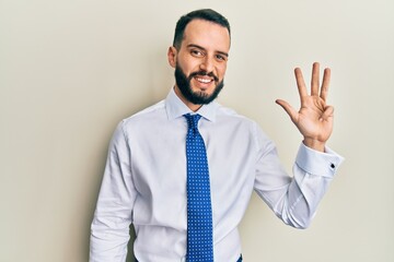 Young man with beard wearing business tie showing and pointing up with fingers number four while smiling confident and happy.