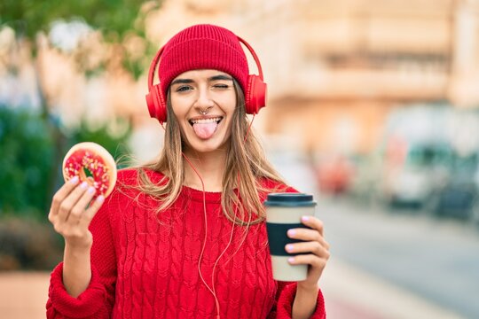 Young hispanic woman having breakfast using headphones at the city.