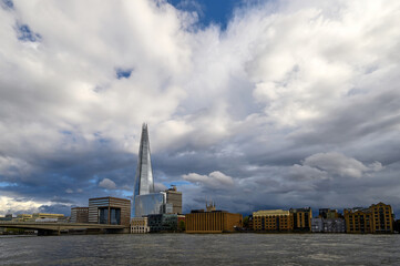 Obraz premium London, UK: View from the City of London looking south across the River Thames with London Bridge and the Shard building. Light reflecting on The Shard with dark storm clouds behind.