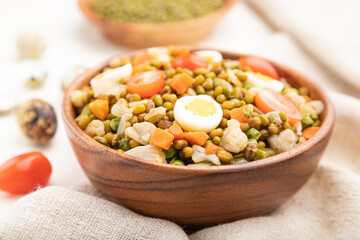 Mung bean porridge with quail eggs, tomatoes and microgreen sprouts on a white wooden background. Side view, selective focus.