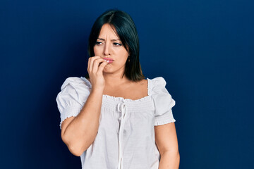 Young hispanic woman wearing casual clothes looking stressed and nervous with hands on mouth biting nails. anxiety problem.