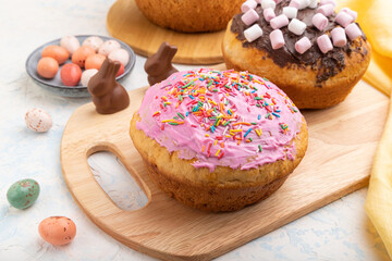 Homemade glazed and decorated easter pies with chocolate eggs and rabbits on a white concrete background. Side view, close up.