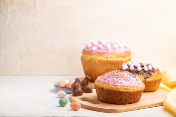 Homemade glazed and decorated easter pies with chocolate eggs and rabbits on a white concrete background. Side view, copy space, selective focus.