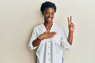 Young african american girl wearing casual clothes smiling swearing with hand on chest and fingers...
