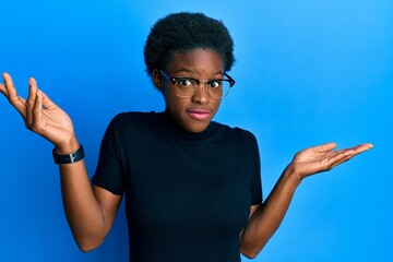 Young african american girl wearing casual clothes and glasses clueless and confused with open...