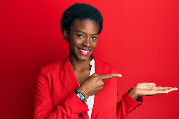 Young african american girl wearing business clothes amazed and smiling to the camera while...