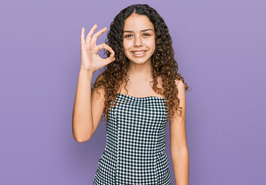 Teenager hispanic girl wearing casual clothes smiling positive doing ok sign with hand and fingers. successful expression.