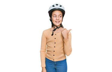 Beautiful brunette little girl wearing bike helmet smiling with happy face looking and pointing to the side with thumb up.